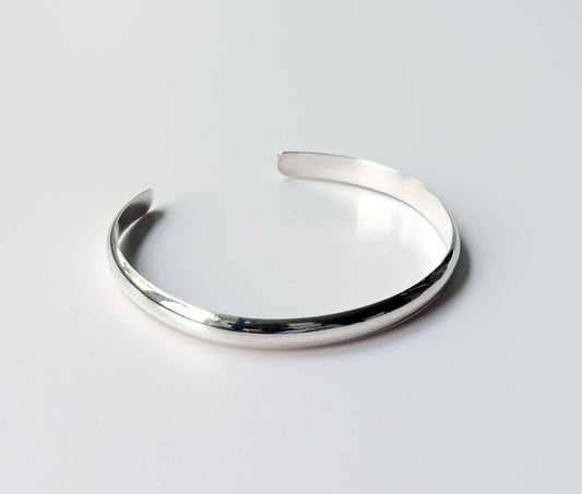 A Silver Cuff bracelet handcrafted in solid Argentium® 935. The gently curved low dome profile gives this cuff its sleek, modern look, while the open design allows for slight adjustability shown on light gray background.