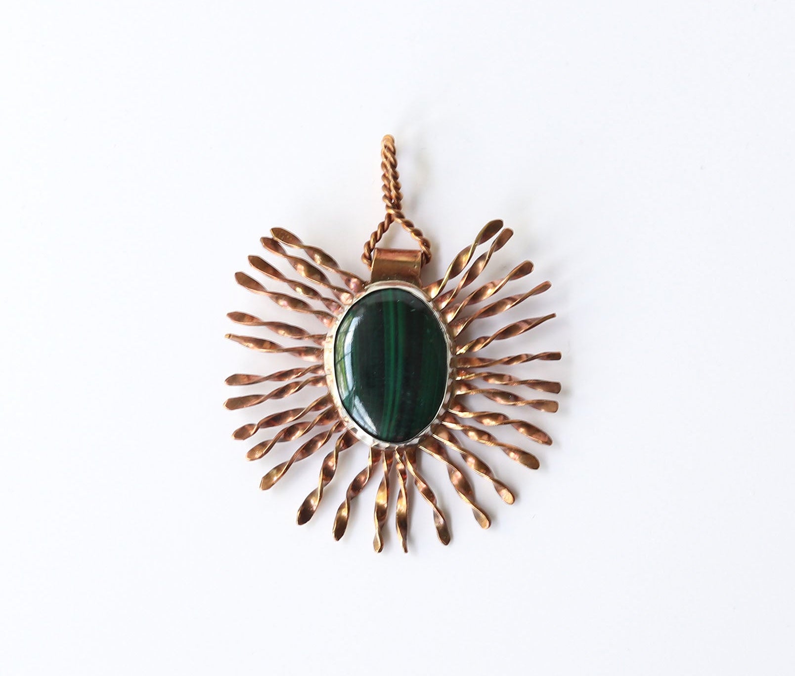 A natural malachite pendant is handcrafted using Argentium silver and Jewelers brass shown on white background.