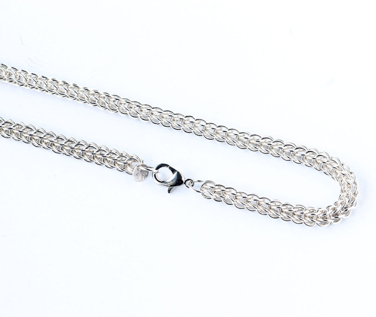 Closeup of teardrop lobster clasp and 6 and 1 Persian weave necklace.  Silver chain necklace on a white background