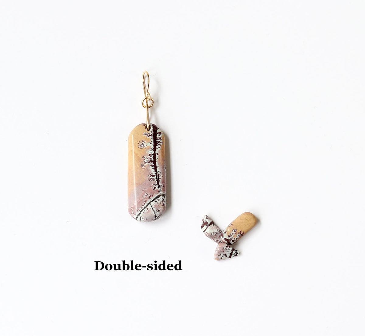 The reverse side of this Natural Sonoran Dendritic Rhyolite | Gold Filled Custom Bail revealing soft pink, tan, and deep brown tones with delicate dendritic patterns formed naturally over time. Shown on white background next to small pebbles of rhyolite used for props.  Text overlay reads Double-sided.