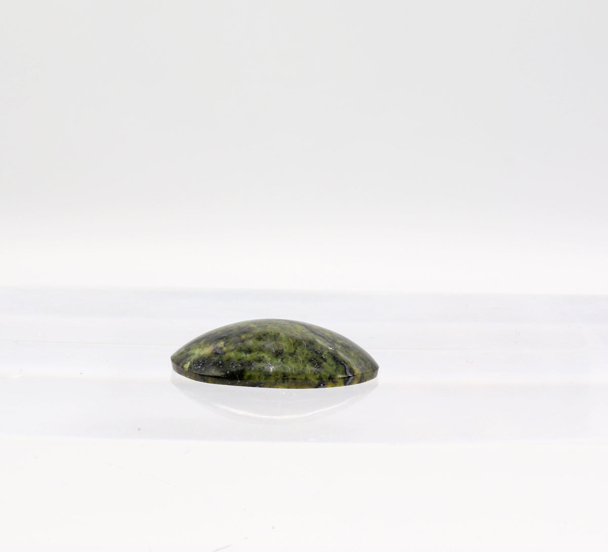 A polished dark green Forest Green Jasper gemstone cabochon displayed on a clear acrylic block against a white background.