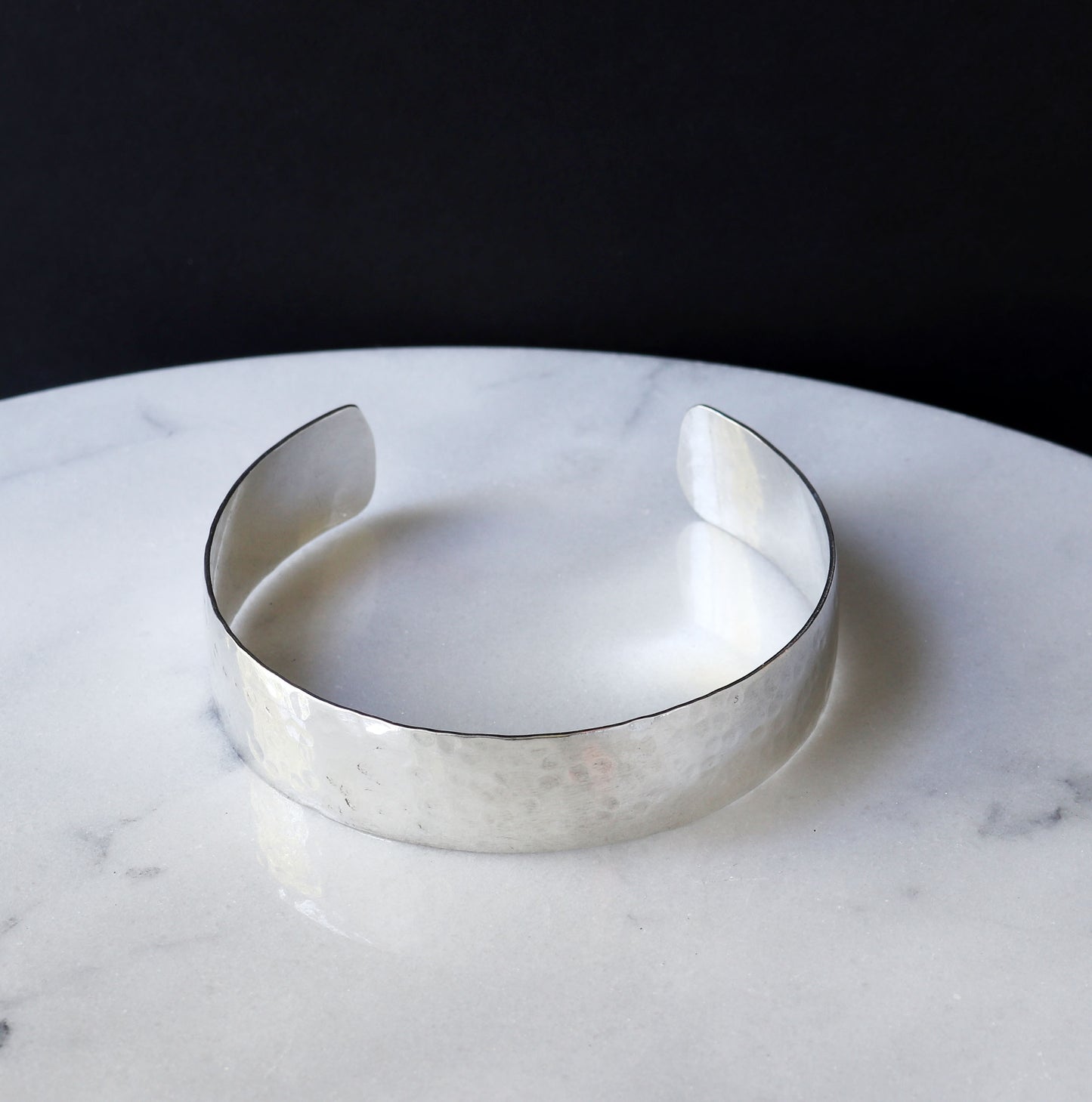 Argentiu, Silver hammered bracelet on a marble surface with a dark background
