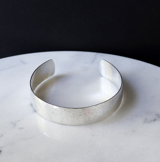 Argentiu, Silver hammered bracelet on a marble surface with a dark background