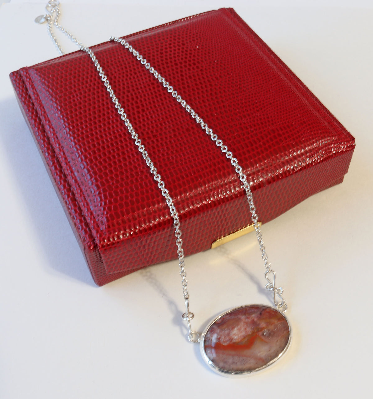 Natural Montana Jasper necklace handcrafted in Argentium 935 Silver with attached silver chain, displayed on a textured red jewelry box against a white background.