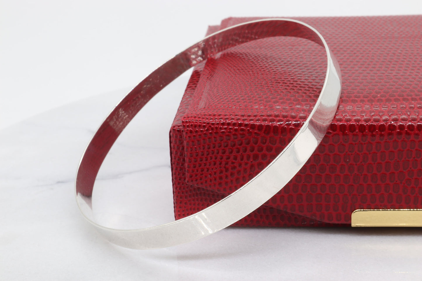 Argentium Silver bangle shown next to red gift box against light gray background.