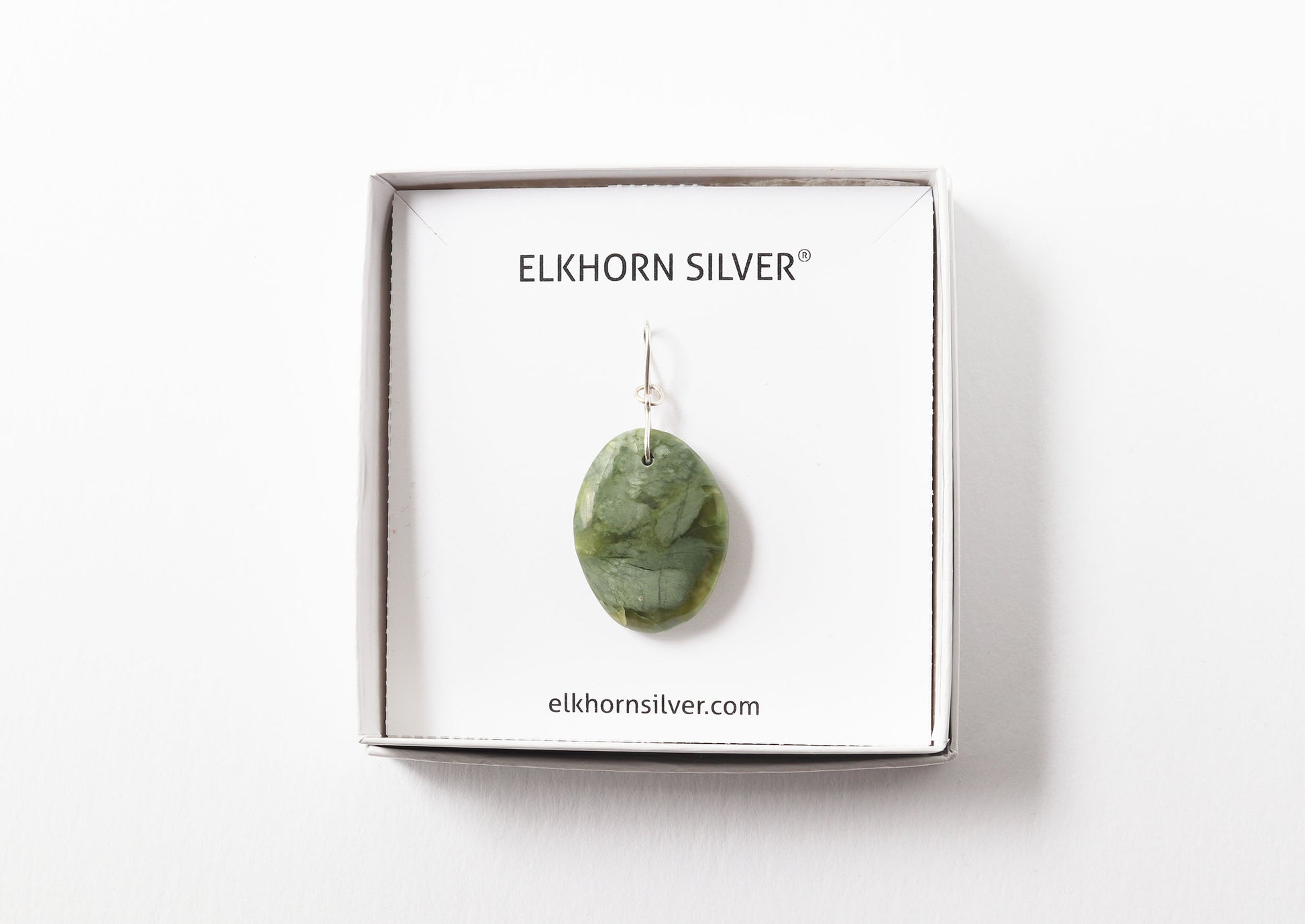 A California jade polished stone pendant displayed in a jewelry box on a white backing card, with the brand name ELKHORN SILVER printed at the top.