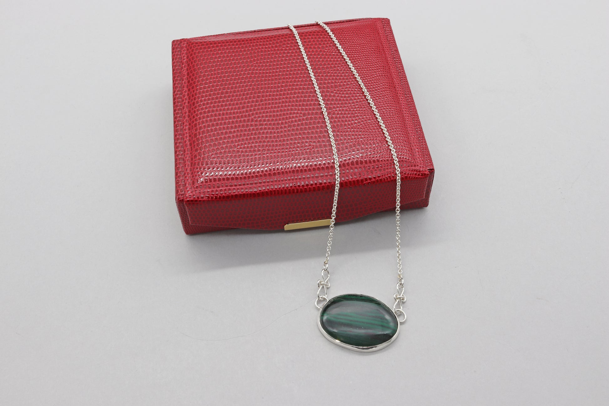 A unique Malachite gemstone pendant hand-cut and polished stone and set in solid sterling 935 Argentium® Silver. Designed with a custom chain and S hook for easy wearability.  Ready to gift in a red faux leather gift box.