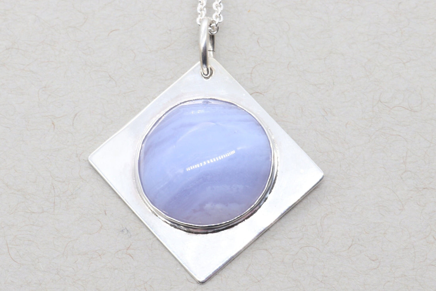 An authentic, high-quality Blue Lace Agate Cabochon, handcrafted in our Missouri USA studio and set within a custom four-point diamond shaped sterling Argentium 935 Silver, and to complete the look a complementary 18" premium silver chain is included.