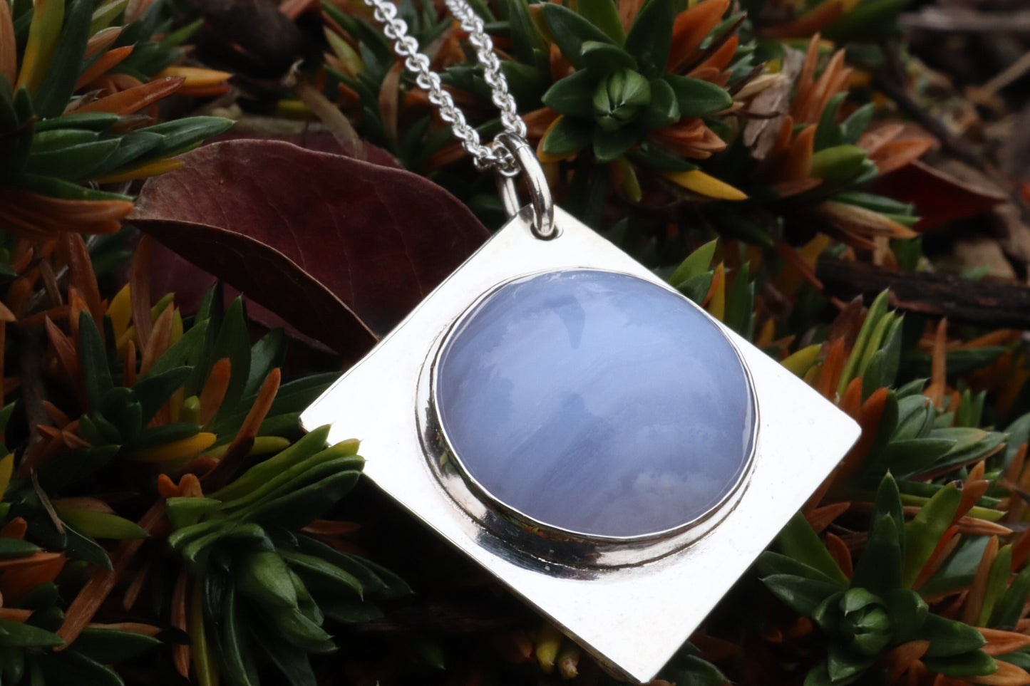 An authentic, high-quality Blue Lace Agate Cabochon, handcrafted in our Missouri USA studio and set within a custom four-point diamond shaped sterling Argentium 935 Silver, and to complete the look a complementary 18" premium silver chain is included.