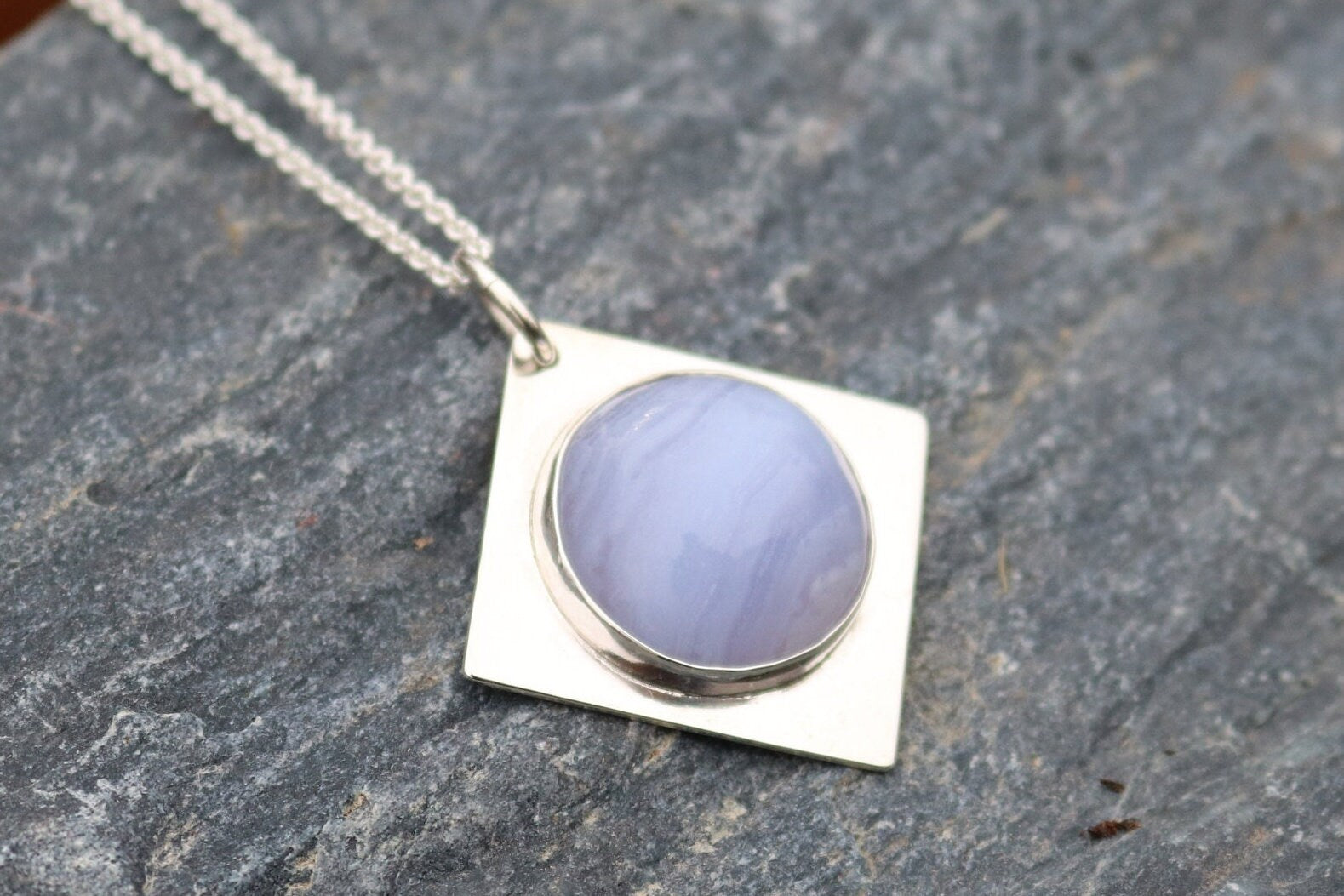 An authentic, high-quality Blue Lace Agate Cabochon, handcrafted in our Missouri USA studio and set within a custom four-point diamond shaped sterling Argentium 935 Silver, and to complete the look a complementary 18" premium silver chain is included.