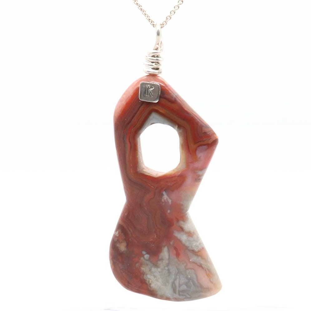 A natural 3.5 inch Crazy Lace Agate Gemstone pendant necklace showcases the mesmerizing beauty of nature's art. Handcut and freeform polished to showcase the unique swirling patterns and vibrant reds, pink and gray hues of the Crazy Lace Agate gemstone.