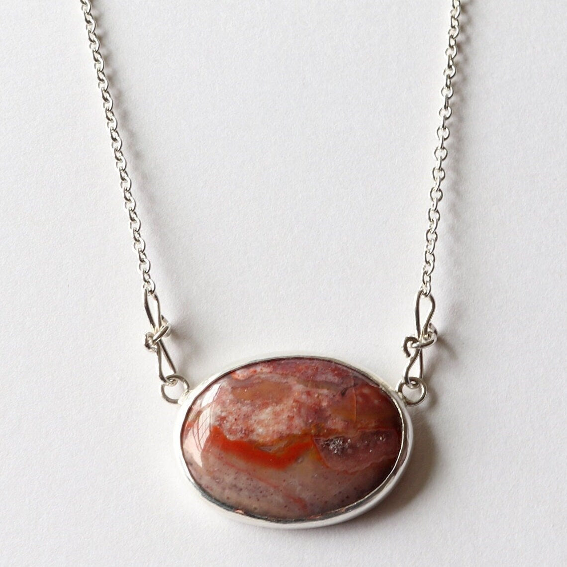 This unique Jasper gemstone was found in the Yellowstone River during a hike in Montana. It has been hand-cut and polished in our Missouri USA studio and set in a handcrafted solid sterling Argentium® 935 Silver bezel paired with an attached crafted custom chain with custom shepherd's hook clasp, resulting in a one-of-a-kind statement Necklace.