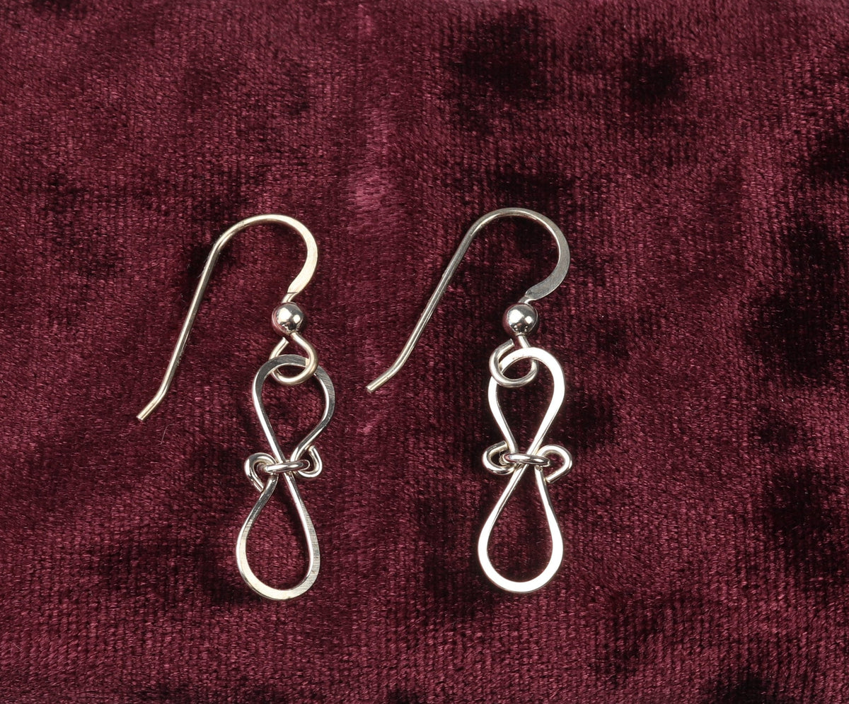 A pair of Argentium Silver Bow Earrings shown against burgundy velvet background.