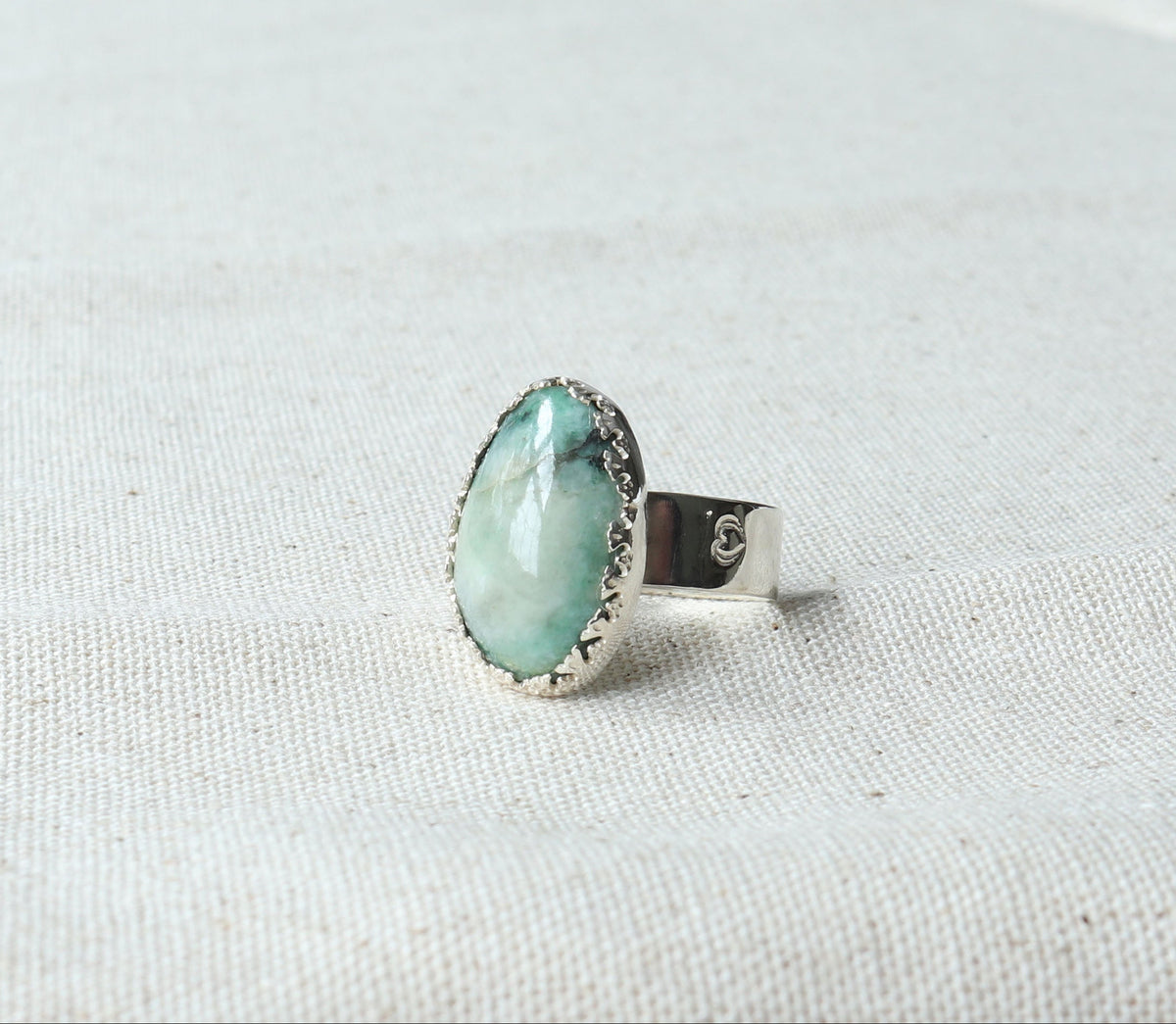African Turquoise Jasper ring handcrafted in polished Argentium 935 silver, resting on a neutral beige fabric background.