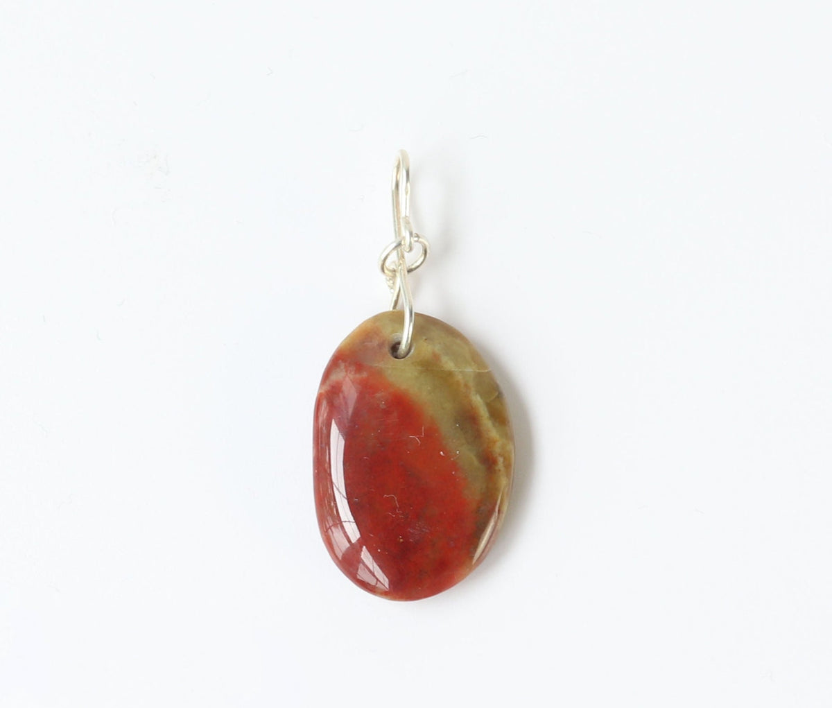 Oval-shaped sonoran sunrise pendant with a red and green color pattern on a white background