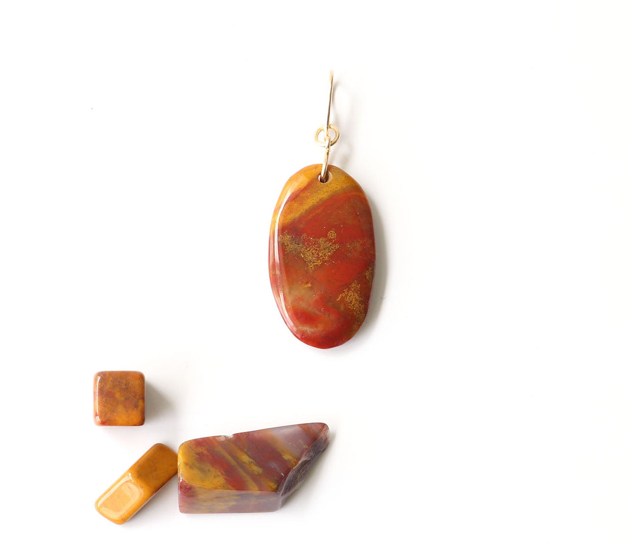 A one-of-a-kind Sonoran Sunrise pendant with a vivid blend of deep red cuprite, golden mustard, and sun-baked earthy hues—cut and polished by hand in our Missouri studio.  Shown on white background with props of raw polished Sonoran Sunrise chips.