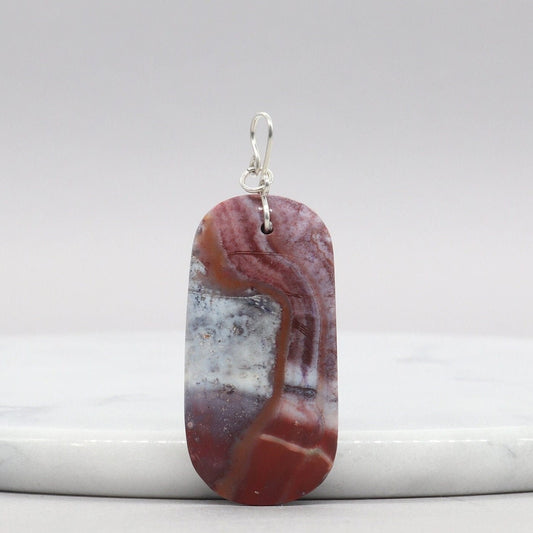 Red Mexican Agate pendant with Argentium Silver bail on white marble against gray background
