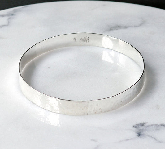 Argentium Silver Bangle shown on white marble with black background.