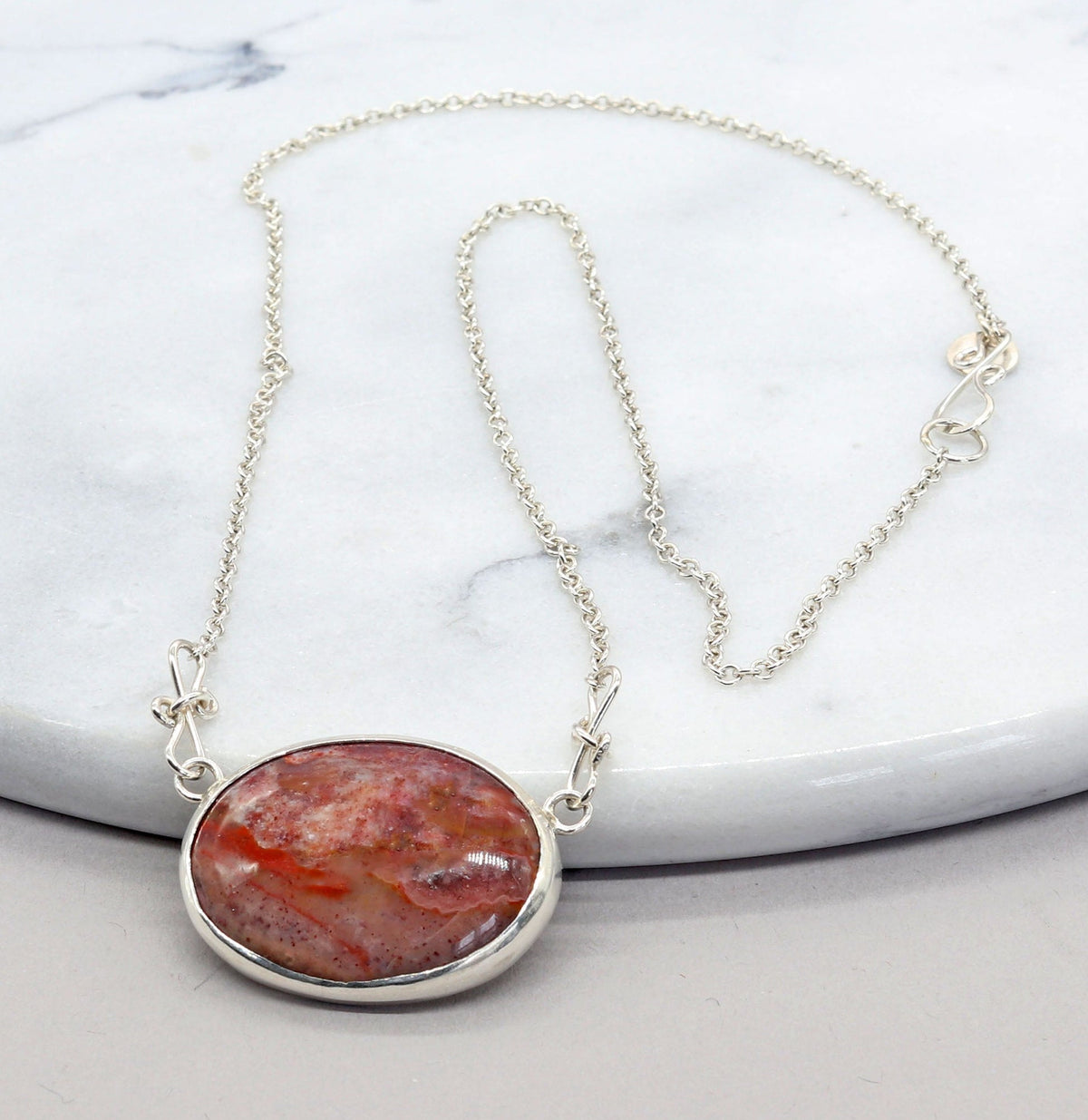 Natural Montana Jasper necklace handcrafted in Argentium 935 Silver with attached silver chain displayed on a white marble slab.