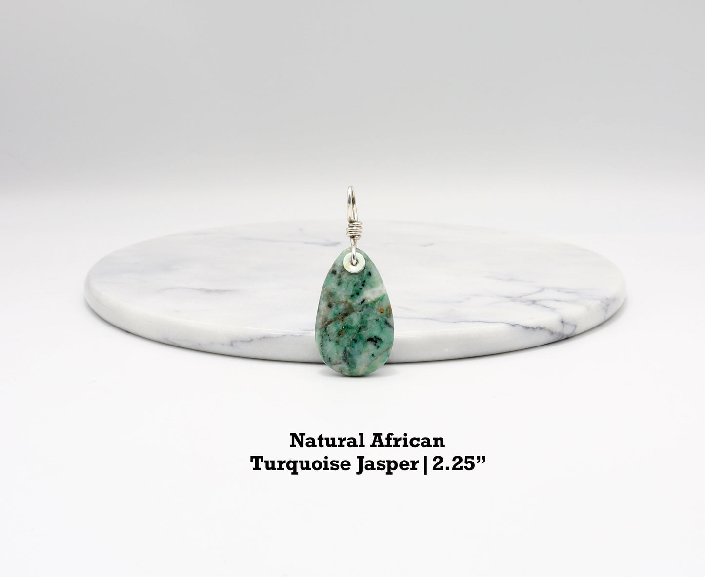 Handcrafted African Turquoise pendant with Argentium 935 Silver bail, 57.15mm, placed next to white marble background, showcasing blue-green hues and matrix patterns.  Text Overlay indicates Natural African Turquoise Jasper 2.25inch.