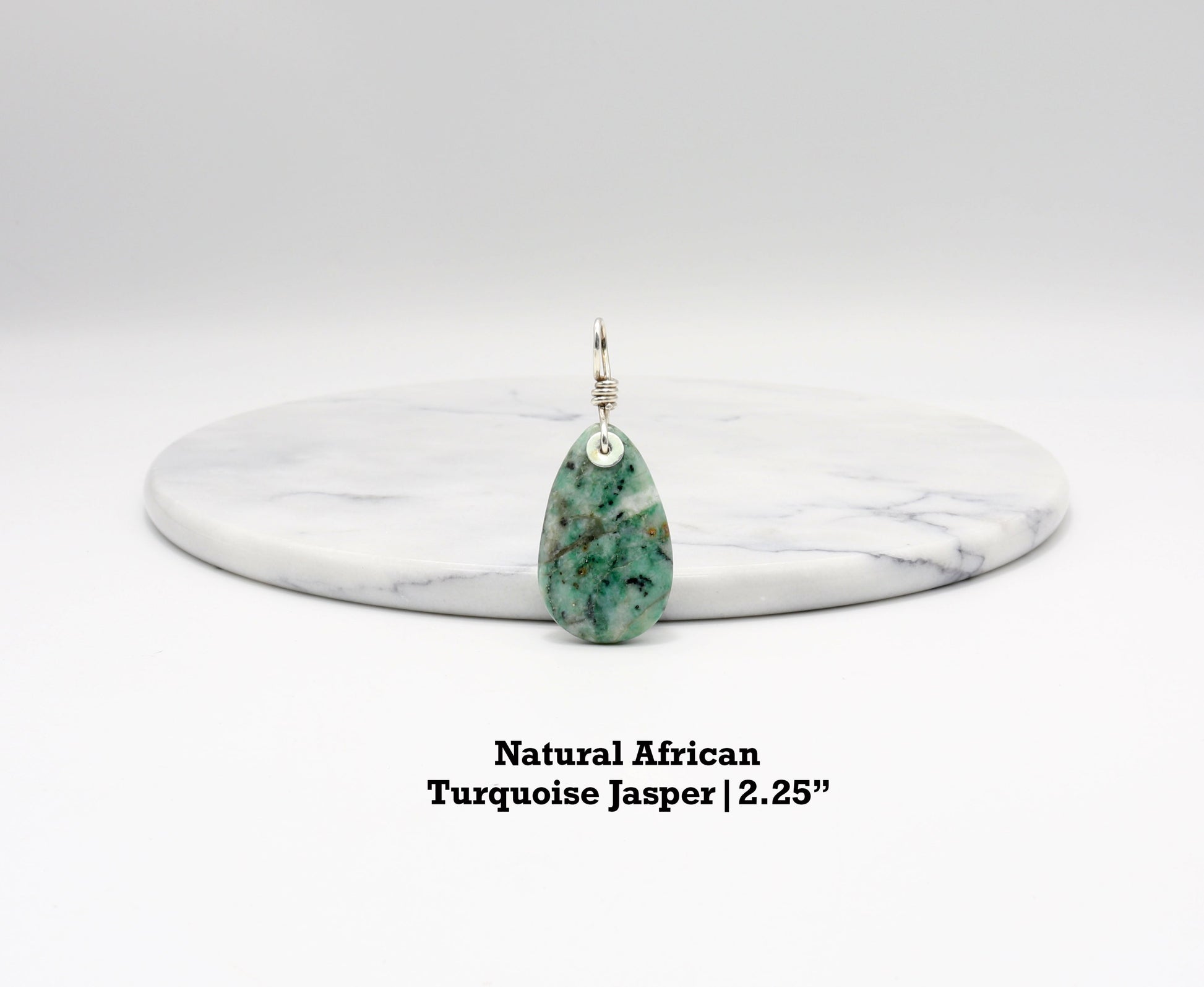 Handcrafted African Turquoise pendant with Argentium 935 Silver bail, 57.15mm, placed next to white marble background, showcasing blue-green hues and matrix patterns.  Text Overlay indicates Natural African Turquoise Jasper 2.25inch.
