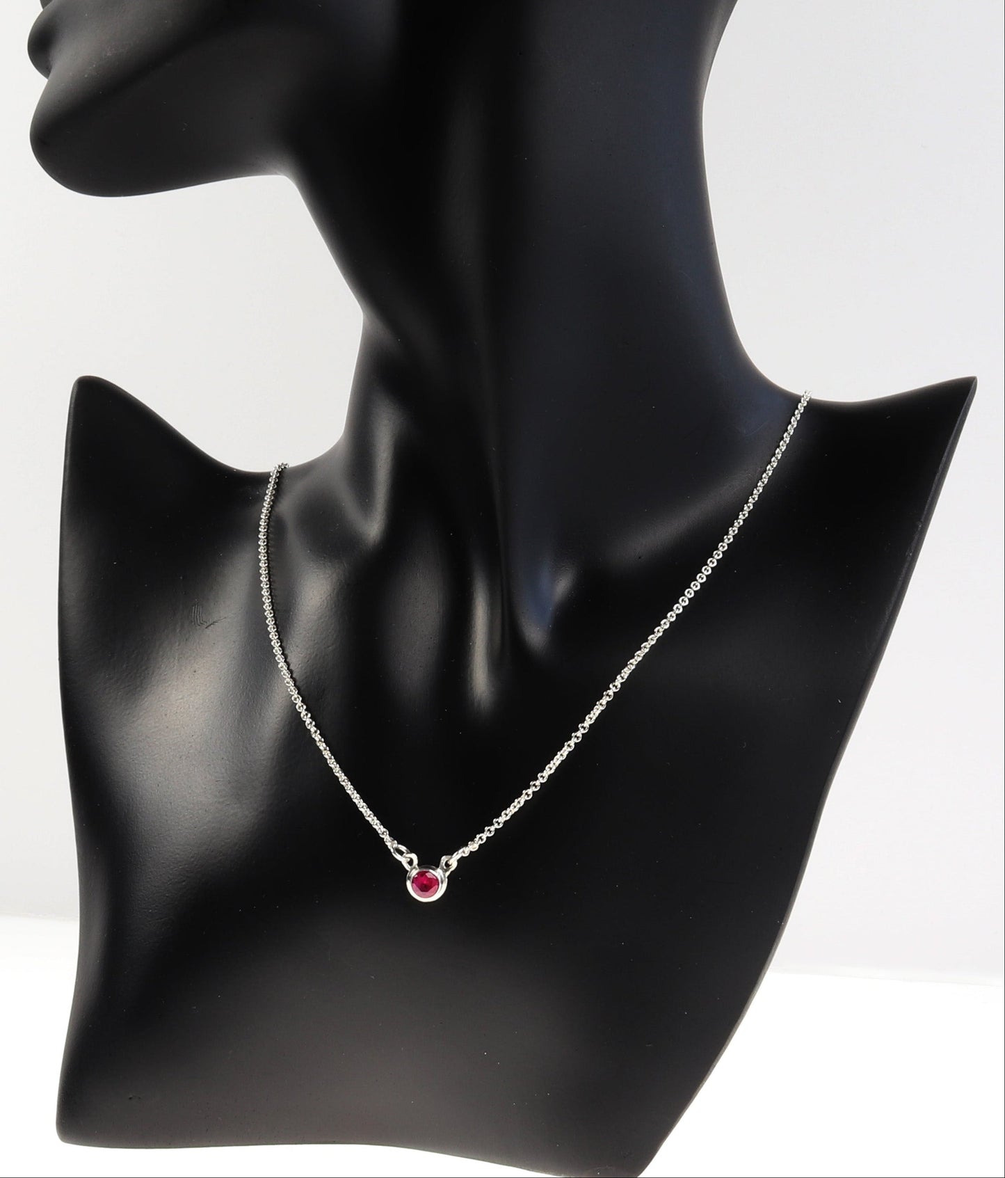 Black mannequin neck with a ruby necklace on a white background