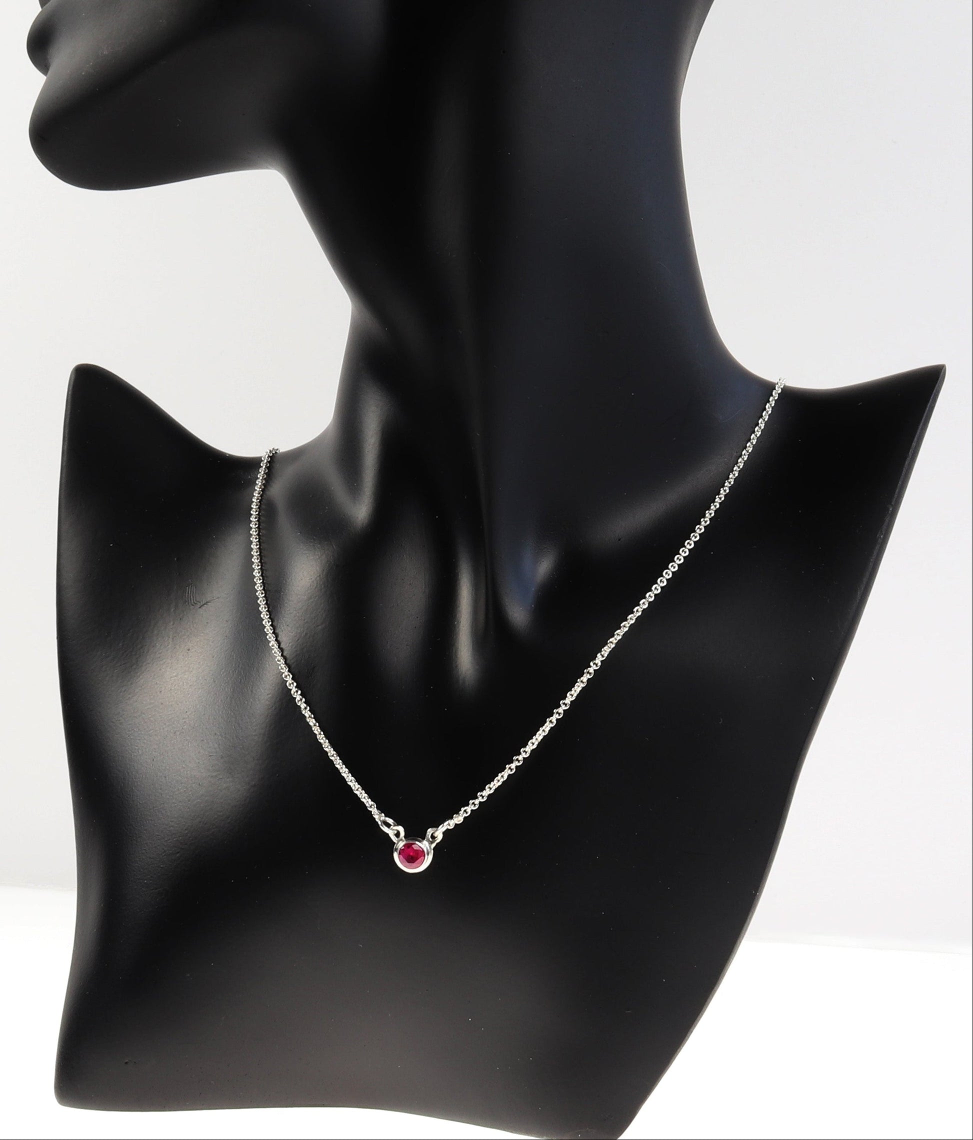 Black mannequin neck with a ruby necklace on a white background