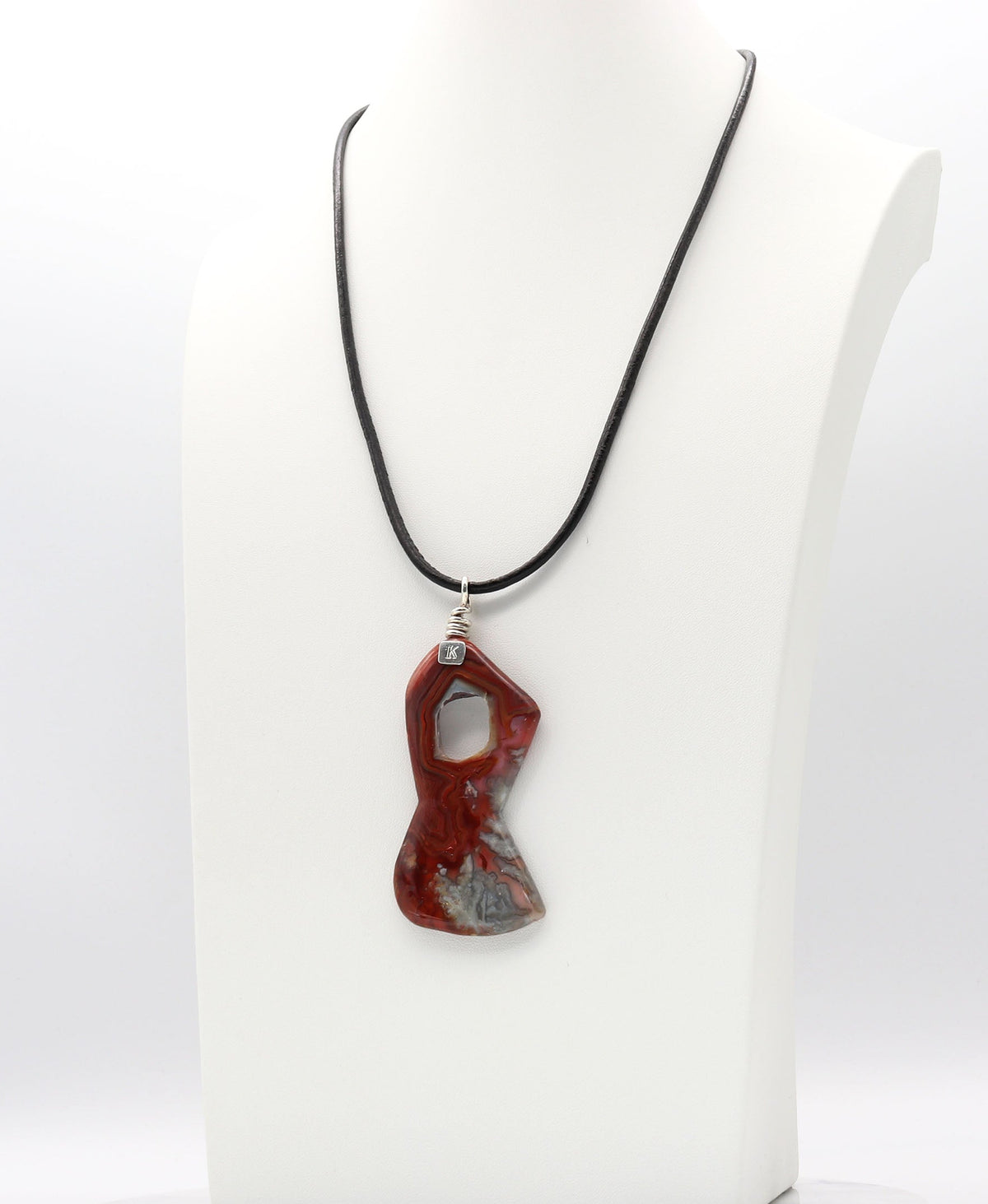 A red and gray agate pendant necklace on a black cord, displayed on a white mannequin bust against a white background.