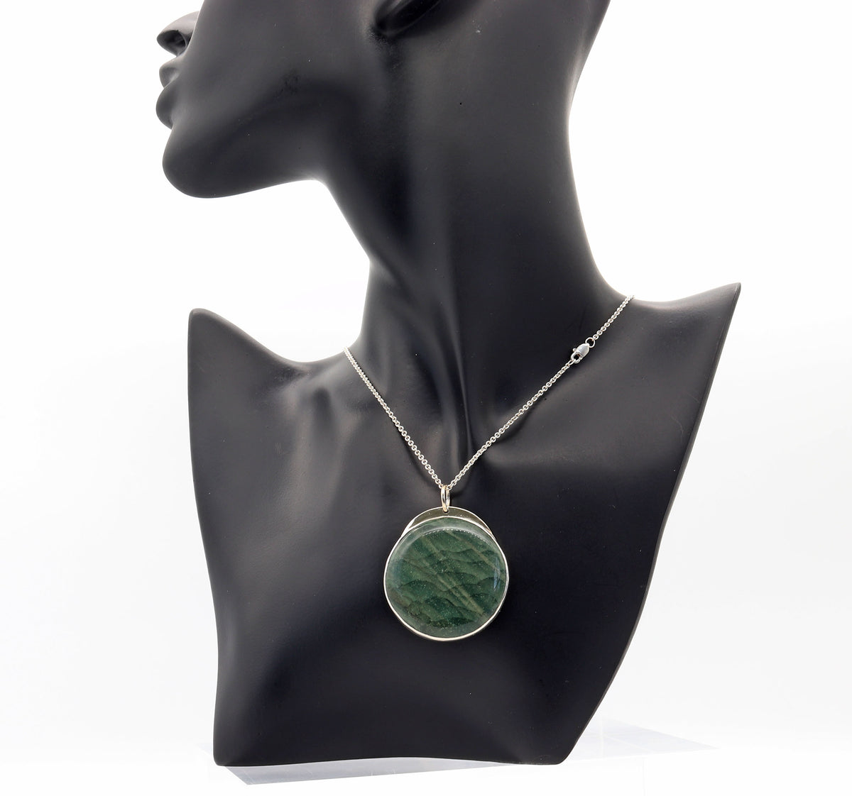 An Argentium silver chain necklace with a round bezel-set Arizona Lizard green stone pendant, displayed on a black mannequin bust against a white background.