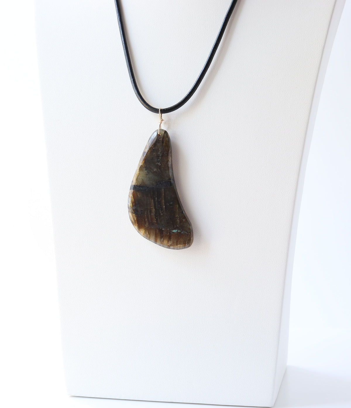 Natural freeform labradorite pendant with gold-filled bail displayed on a black cord against a white jewelry bust.