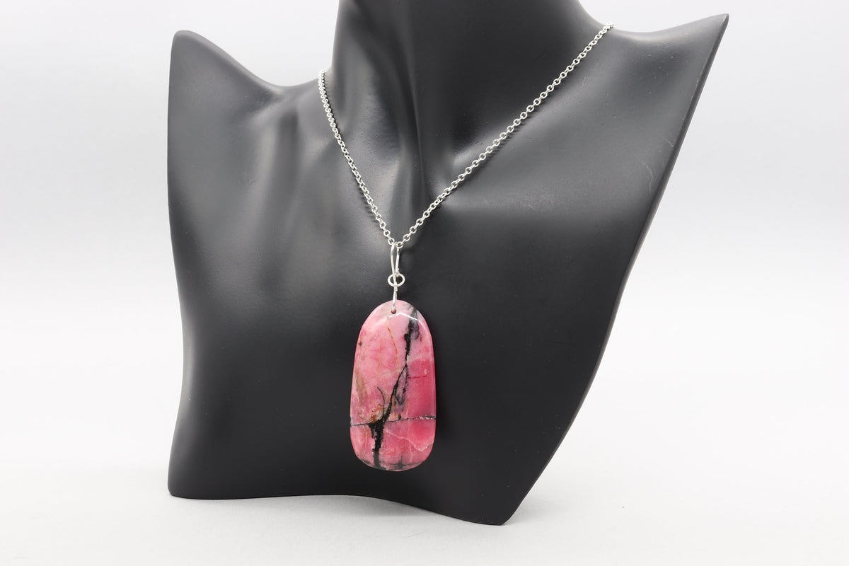 Natural Rhodonite pendant necklace with solid Argentium 935 Silver bail and chain displayed on black resin jewelry form and shown on light gray background.