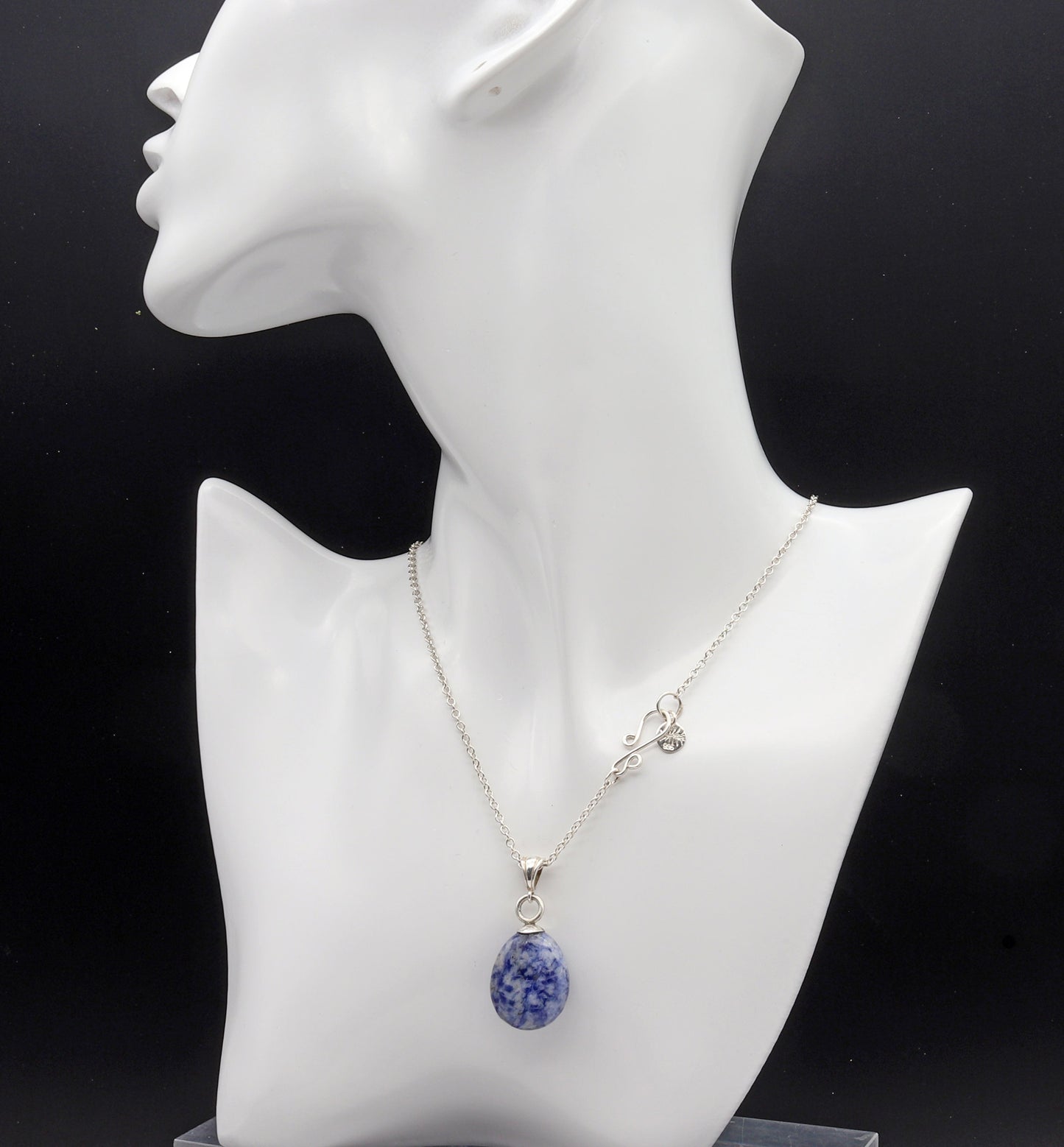 One-of-a-kind Blue Sodalite teardrop pendant, hand-cut and polished in our Missouri studio shown on white resin jewelry form on black background.  Paired with Argentium Silver necklace with s-hook clasp.
