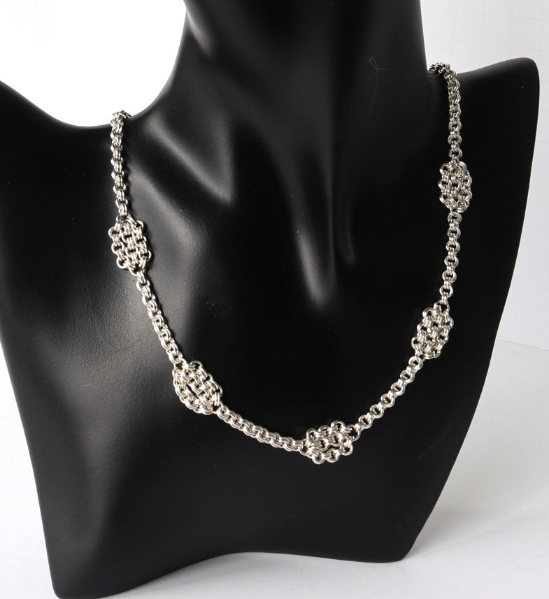 Silver chain necklace on a black mannequin bust with a white background
