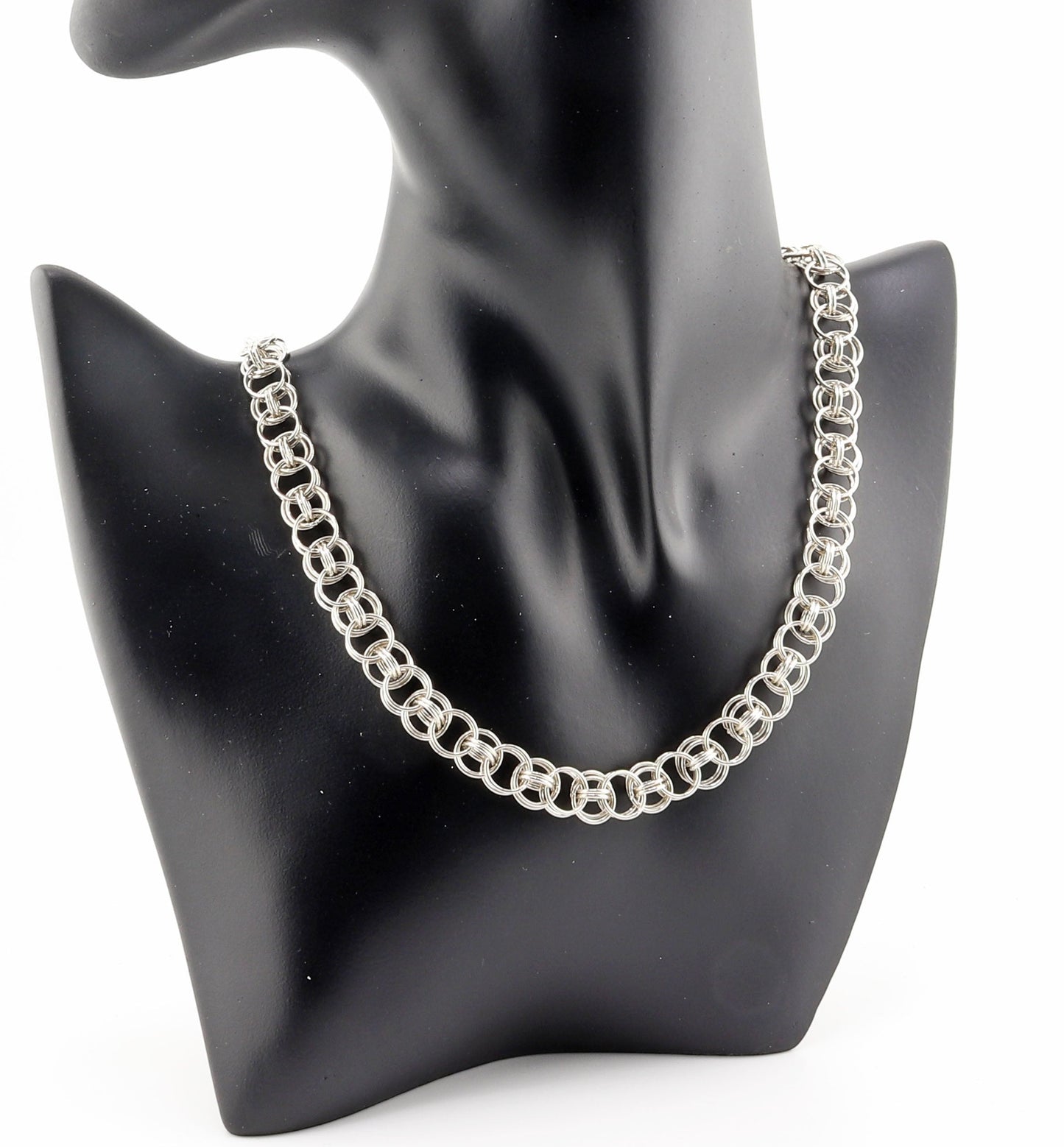 Black resin jewelry boutique mannequin modeling 18-inch Argentium silver helm weave necklace against white background.