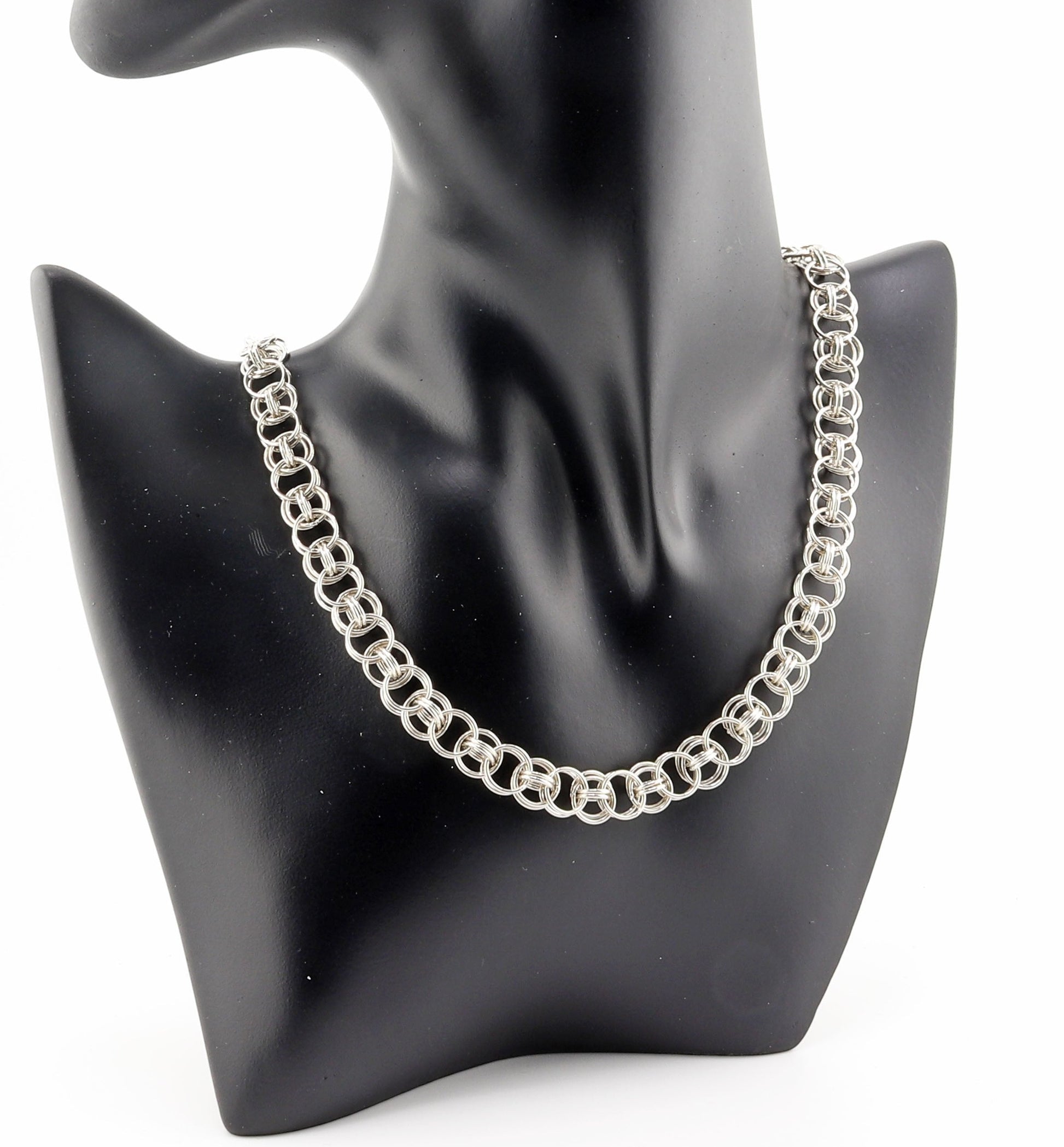 Black resin jewelry boutique mannequin modeling 18-inch Argentium silver helm weave necklace against white background.
