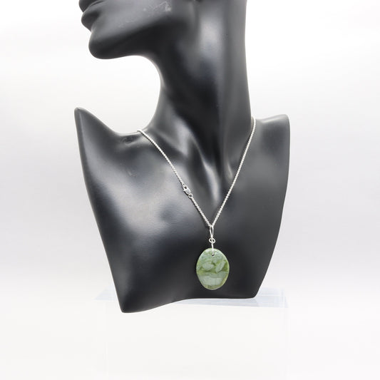 A California Jade gemstone pendant. Handcut and polished to showcase its unique translucent qualities, green hues and striking patterns on both sides.  The pendant is designed with an original infinity bow shaped wire bail made from sterling Argentium® 935 Silver that is tarnish resistance and has a remarkable shine.  The complete the look a complementary 935 Argentium silver chain is included.