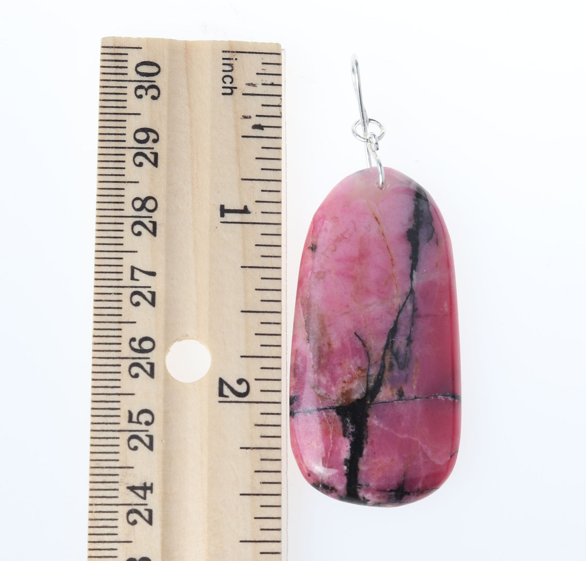 Natural Rhodonite pendant necklace with solid Argentium 935 Silver bail shown next to a wooden ruler for size reference on a white background.