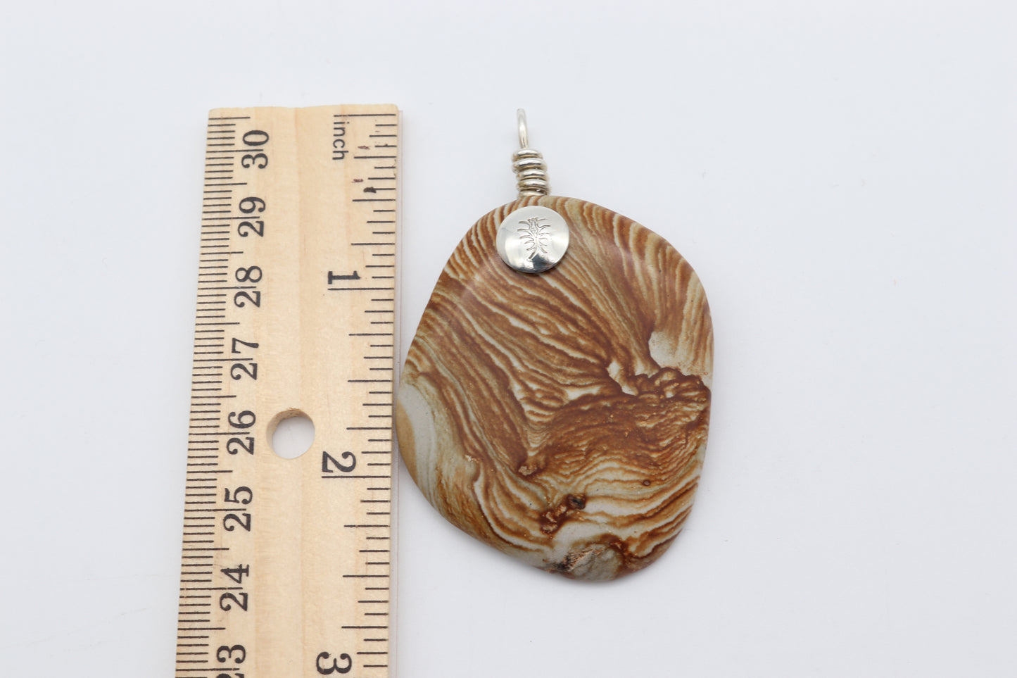 A natural 2.5 inch Picture Jasper gemstone, handcut and polished on both sides to showcase the earthy tones, warm browns, creamy beiges, and nature's intricate patterns.  The custom handcrafted coil bail is from sterling Argentium® 935 Silver renowned for its resistance to tarnishing and its durable quality.
To complete the look a complementary 3 mm Leather Cord Necklace is included.