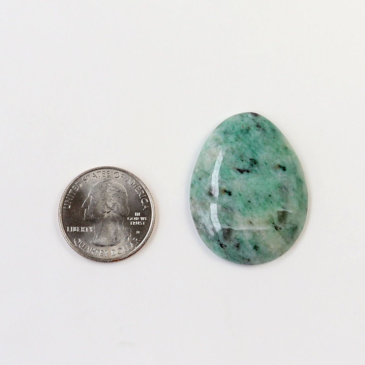Hand-cut African Turquoise Jasper teardrop cabochon with natural teal-green, cream, and dark mineral patterning shown next to U.S. quarter for scale on a white background