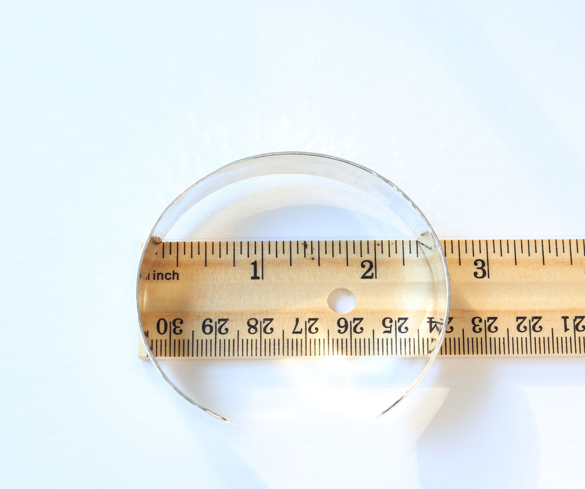  Sterling Silver Cuff placed over a wooden ruler to show its size in inches, photographed on a white background.