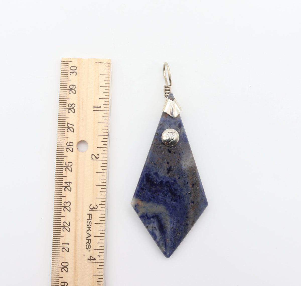 Blue Foidolite pendant necklace with solid Argentium Silver bail and chain next to a wood ruler for scale.