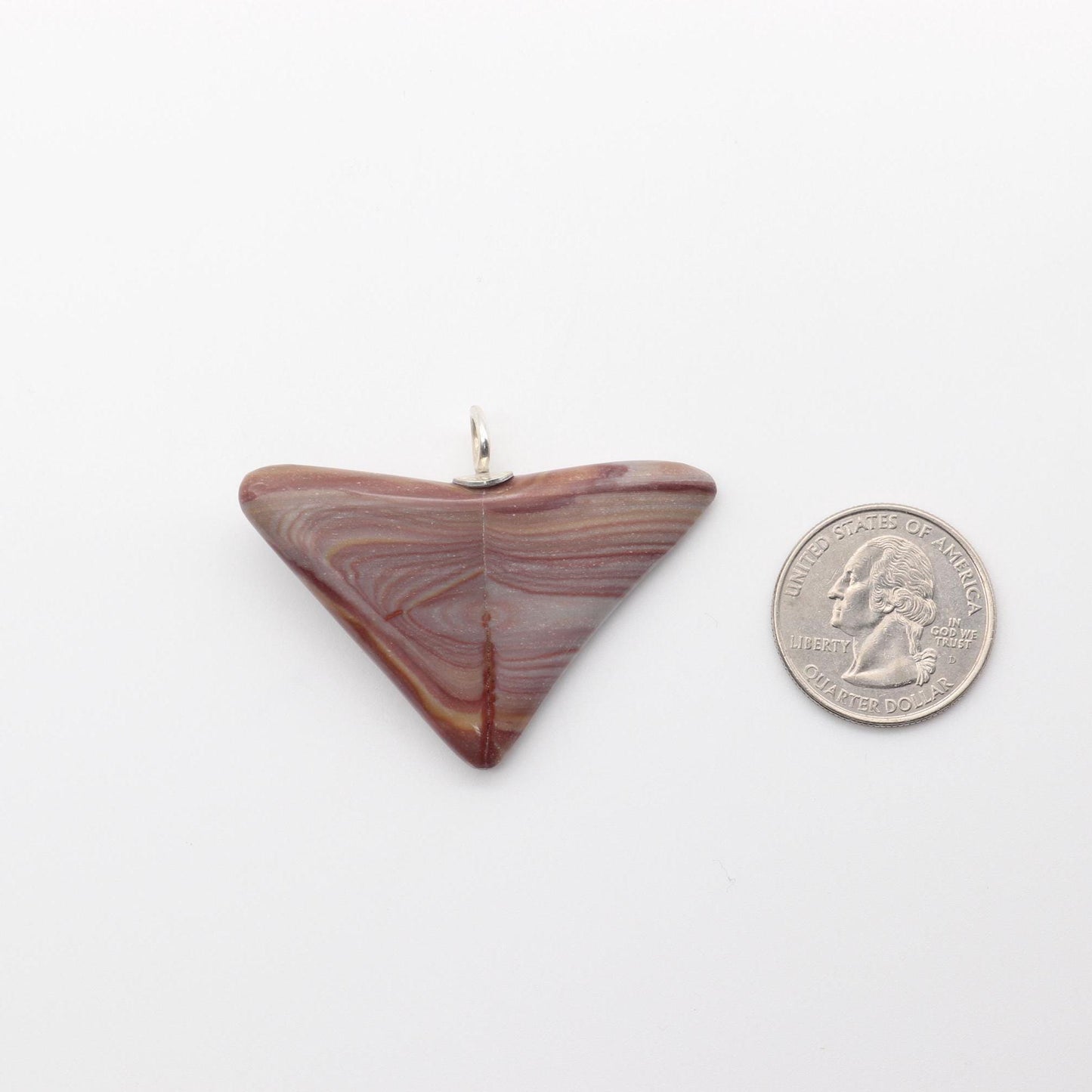Front-facing view of this handcut polished Butterfly Shaped Petrified Rainbow Wood pendant featuring earthy tones of deep crimson, purple, and tangerine with handcrafted Argentium 935 silver bail shown next to US quarter for scale on white background.