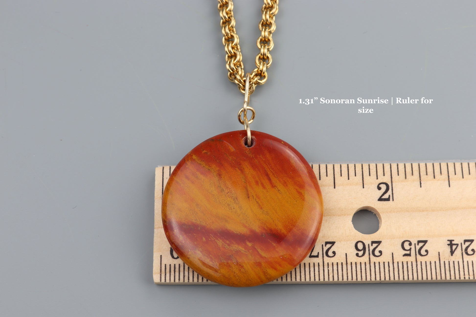 Red Sonoran Sunrise Cuprite Pendant –  on a gray background, ruler for scale.