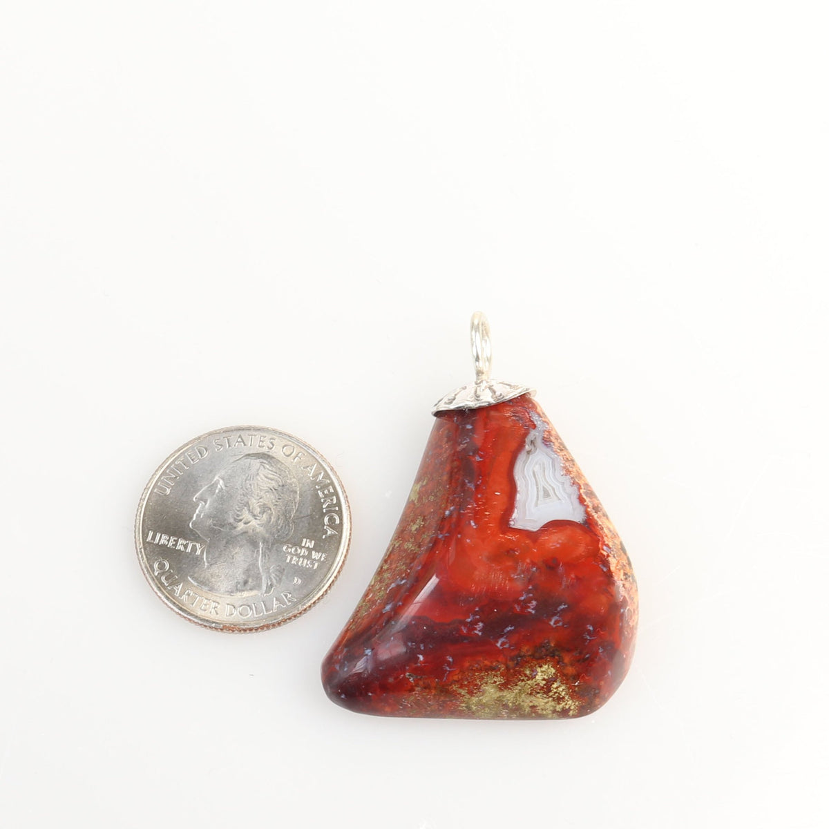 One-of-a-kind Red Jasper Agate freeform pendant with Argentium 935 Silver bail next to a U.S. quarter for scale shown on white background.