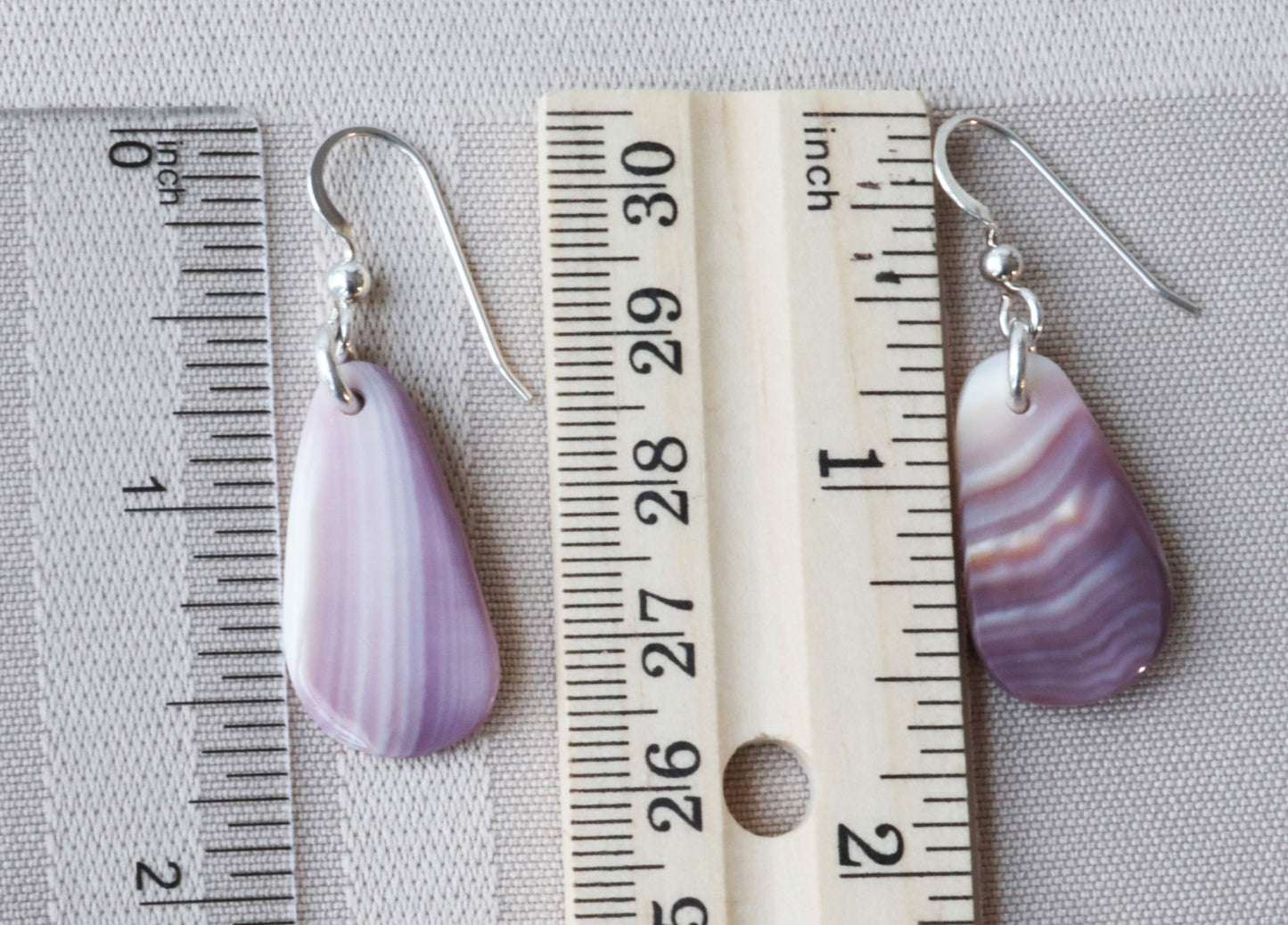 Earrings next to rulers to illustrate size perspective.