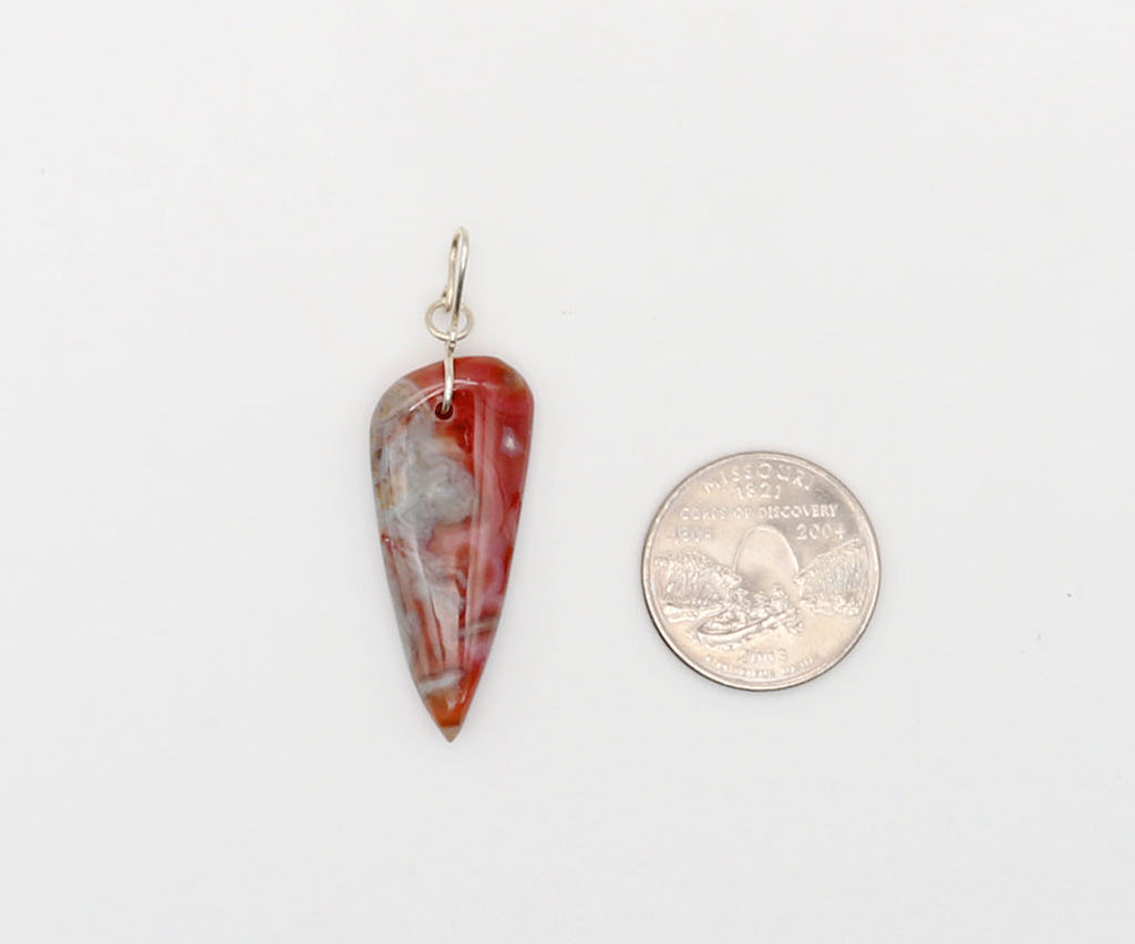 A small tear-drop shaped Crazy Lace Agate pendant with a silver bail, shown next to a US quarter for scale on a plain white background.