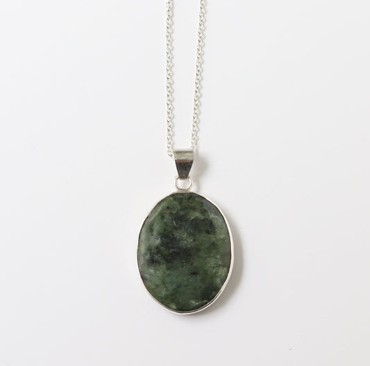 An Argentium silver chain necklace with an oval Wyoming jade pendant, set in a silver open bezel, on a plain white background.