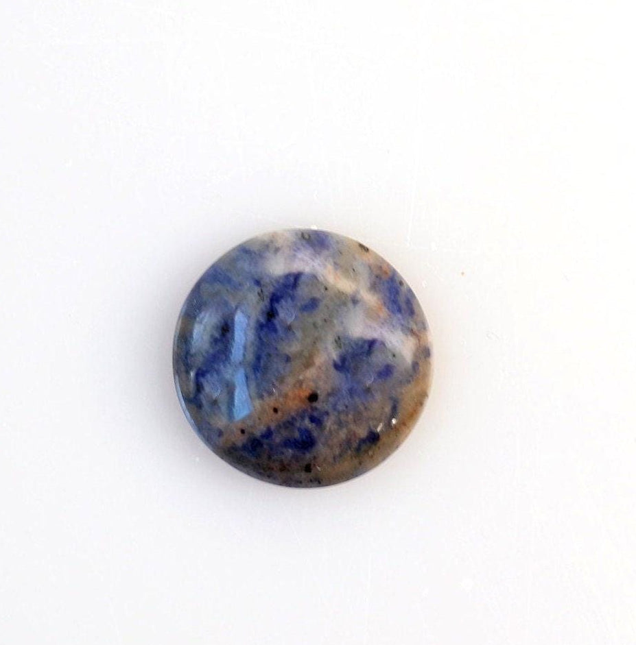 A single round Blue Foidolite Sodalite cabochon hand-cut 19.64 mm with a marbled pattern of deep blue, slate gray, and brown, photographed on a clean white background.