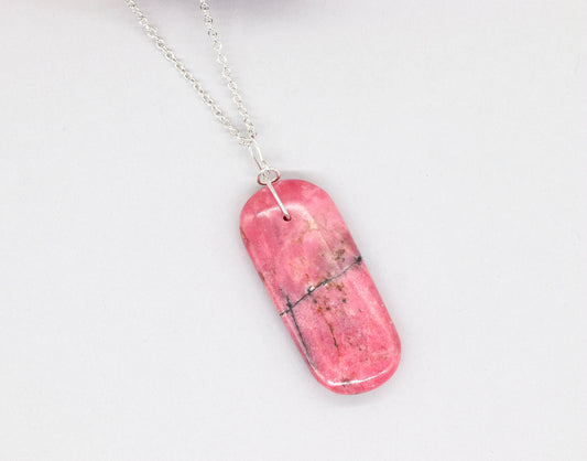 Natural Rhodonite pendant necklace with solid Argentium 935 Silver bail and chain shown on light gray background.