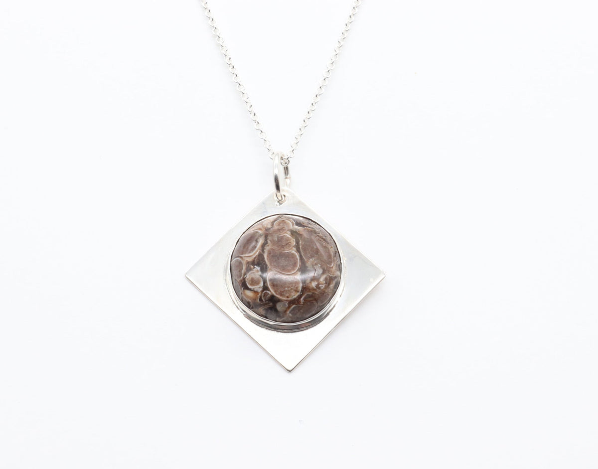 Necklace with a pendant featuring a circular design on a white background